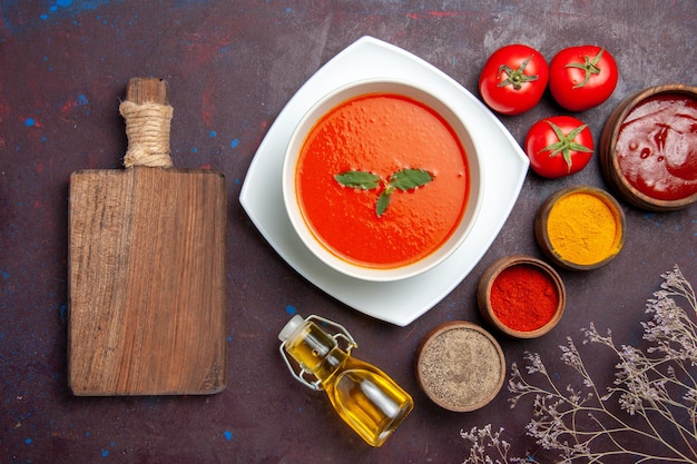 Top view delicious tomato soup with different seasonings on dark background dish sauce tomato color meal soup