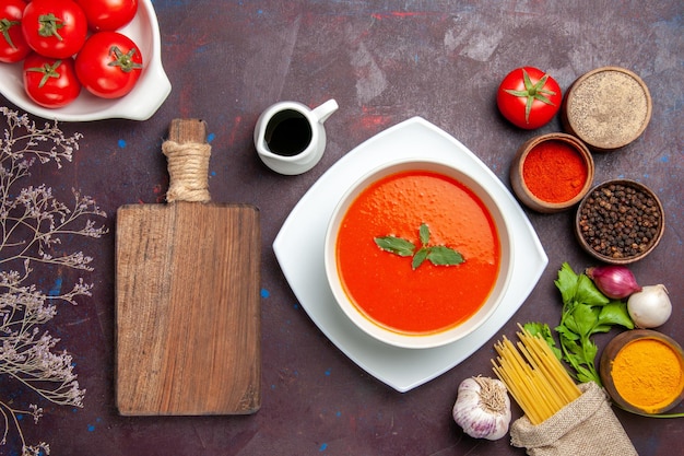 Top view delicious tomato soup with fresh tomatoes and seasonings on a dark background dish meal sauce tomato color soup