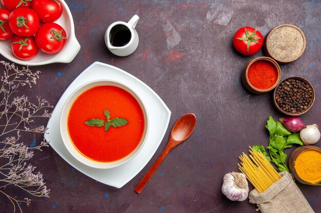 Top view delicious tomato soup with fresh tomatoes and seasonings on dark background dish meal sauce tomato color soup