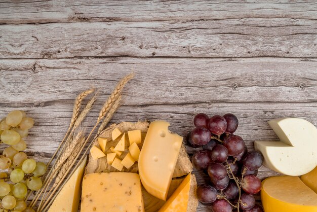 Top view delicious variety of cheese with grapes on the table