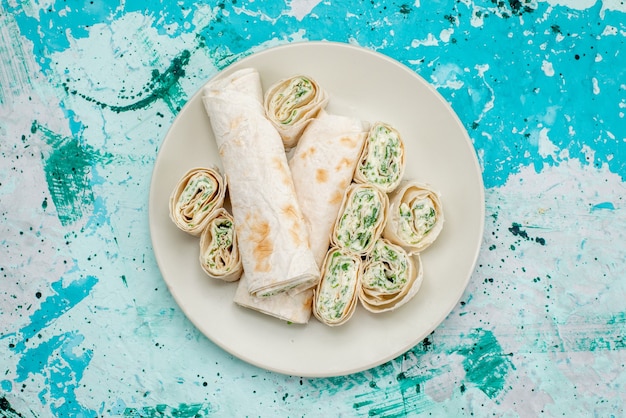 Free Photo top view of delicious vegetable rolls whole and sliced on bright-blue, food meal roll vegetable snack