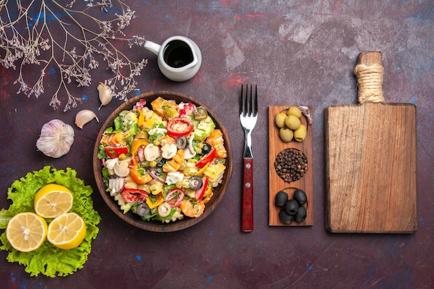 Top view delicious vegetable salad with lemon slices and green salad on a dark background meal diet salad health