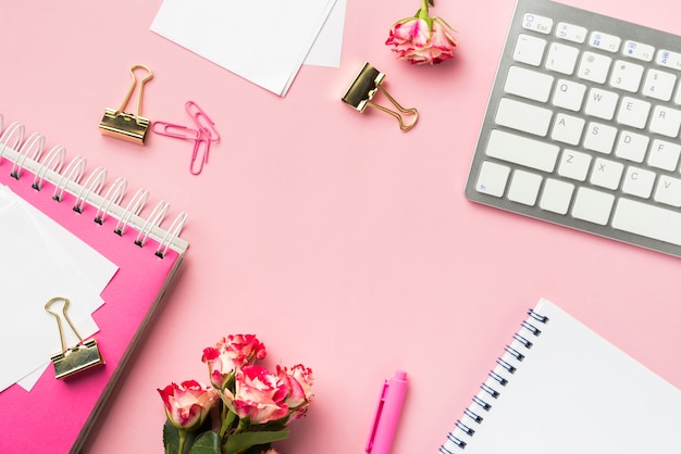 Top view of desk stationery with bouquet of roses