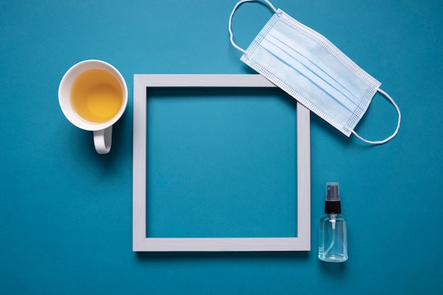 Top view of desk with frame and medical mask next to tea