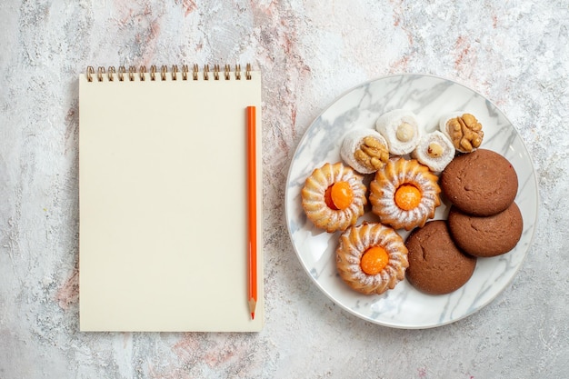 Top view different cakes little sweets on light-white background cookie biscuit sugar tea sweet cake