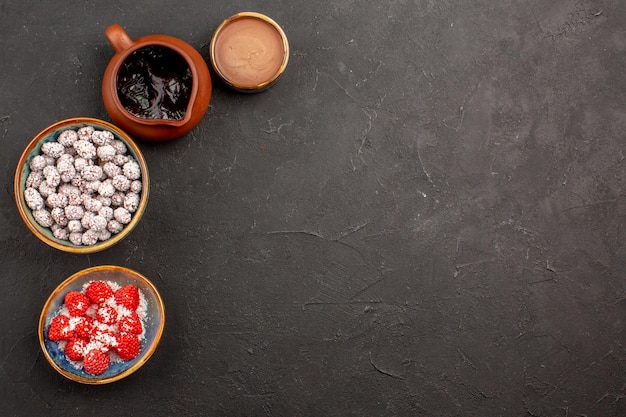 Top view different candies with chocolate syrup on a dark surface color candy tea biscuit