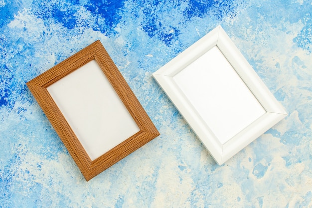 Top view different colors empty photo frames on blue white grunge