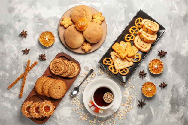 Top view different cookies with cakes and cup of tea on white surface cookie biscuit sugar bake cake sweet pie