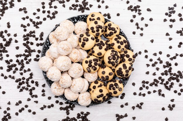 Top view different cookies with chocolate pieces on white surface