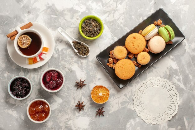 Free Photo top view different cookies with jams and cup of tea on the white desk biscuit sugar pie cake sweet cookies