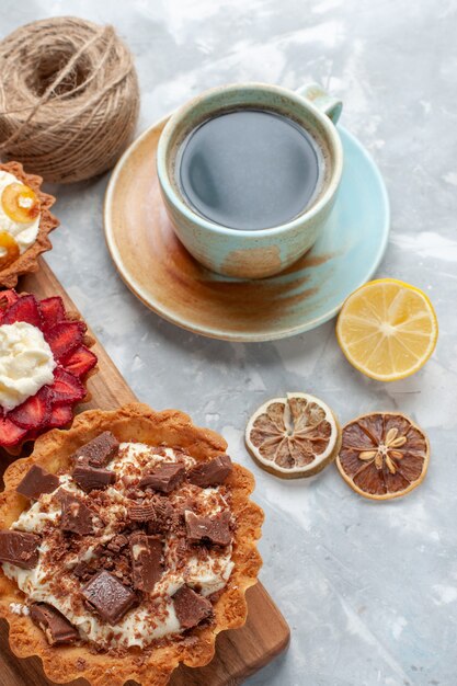 Top view different creamy cakes with chocolate and fruits tea on the white desk cake bake biscuit sweet sugar fruit