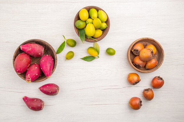 Top view different fresh fruits inside plates on the white background fruit tropical ripe diet exotic color healthy life