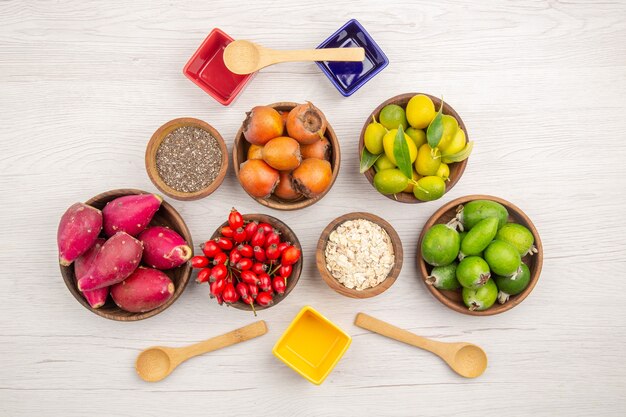 Top view different fresh fruits inside plates on the white background ripe exotic healthy life tropical color diet