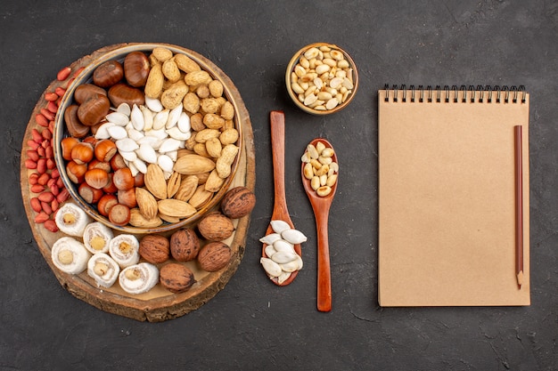 Top view of different fresh nuts on dark surface