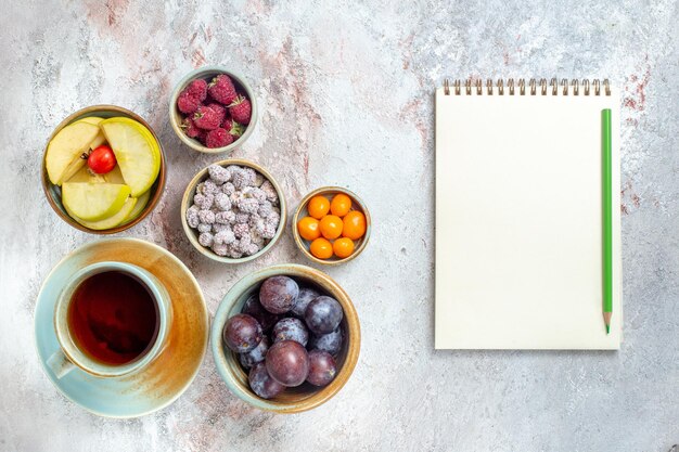 Top view different fruits composition fresh fruits with little cake and tea on white background mellow fruits vitamine health ripe