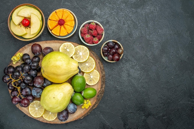 Top view different fruits composition fresh and ripe on dark-grey background mellow fruits health ripe fresh