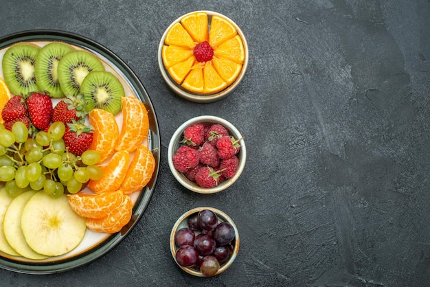 Top view different fruits composition fresh and sliced fruits on dark background health fresh mellow ripe fruits