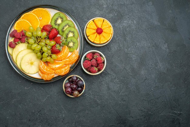 Top view different fruits composition fresh and sliced fruits on the dark background health fresh mellow ripe fruits