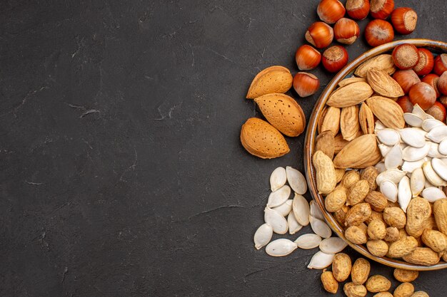 Top view of different nuts fresh nuts inside tray on dark surface