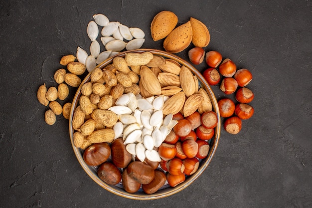 Top view of different nuts fresh nuts inside tray on dark surface