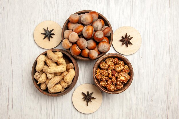 Top view different nuts inside little pots on white desk snack walnut hazelnut nut