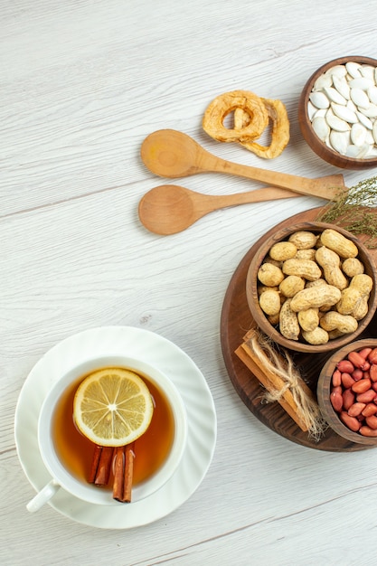 Top view different nuts peanuts hazelnuts and walnuts with cup of tea on white table