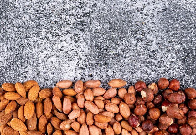 Top view different nuts with pecan, pistachios, almond, peanut, cashew, pine nuts on dark stone table