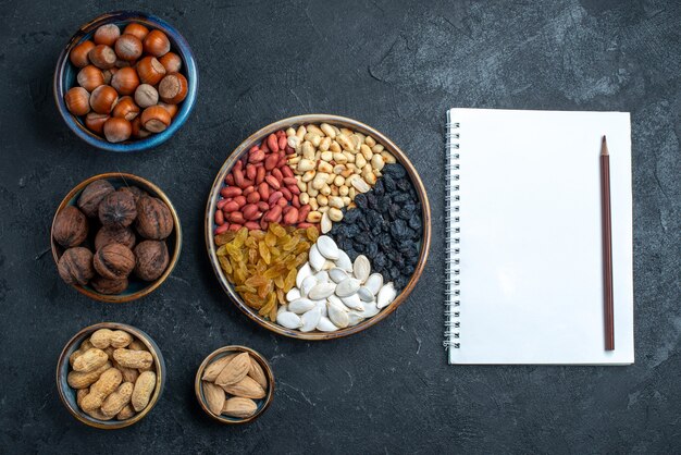 Top view different nuts with raisins and dried fruits on the dark-grey background nut snack hazelnut walnut peanut