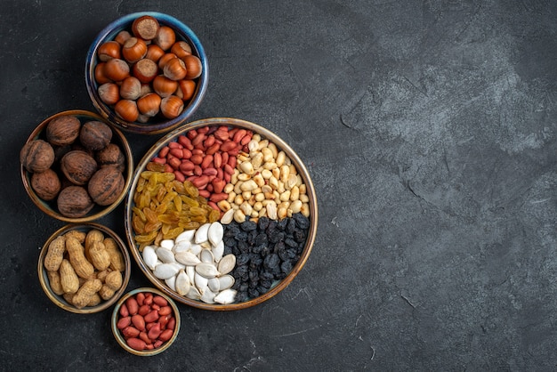 Free Photo top view different nuts with raisins and dried fruits on the grey background nut snack raisin dry fruit nuts