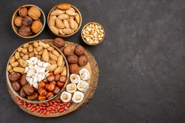 Top view of different nuts with white confitures on dark surface