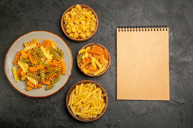 Free photo top view of different pasta composition raw product inside plates on grey