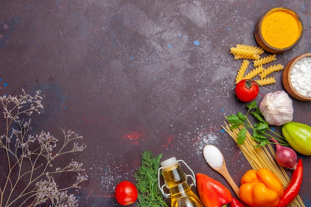 Top view different products raw pasta different seasonings and vegetables on dark background health diet raw food