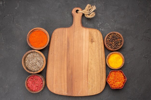 Top view of different seasonings spicy ingredients inside little pots on black