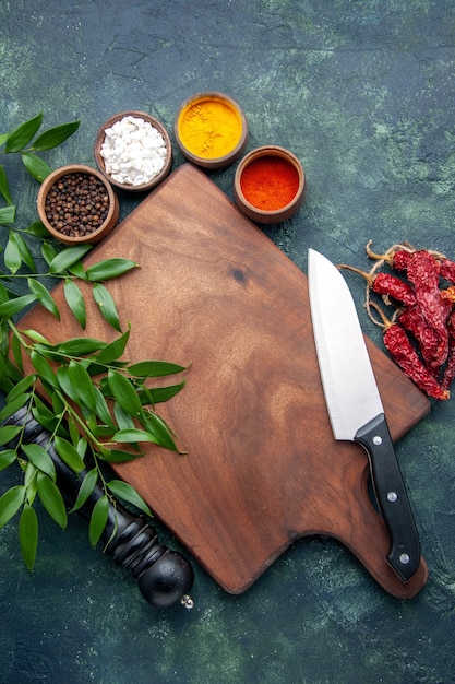 Free Photo top view different seasonings with brown wooden desk on a dark-blue surface color wood sharp cutlery tree green kitchen