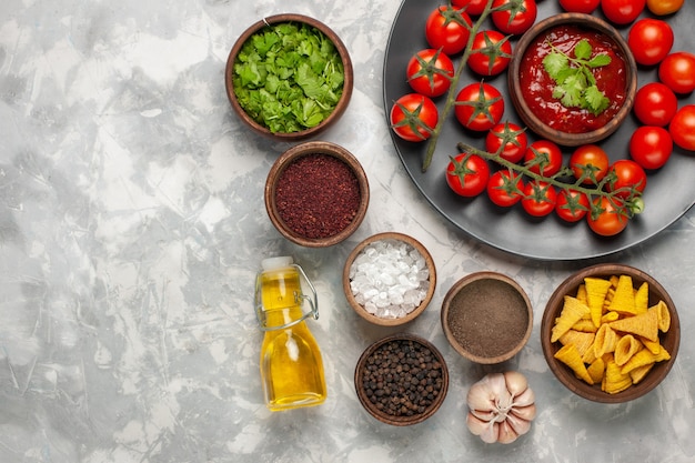 Free photo top view different seasonings with cherry tomatoes and oil on white desk