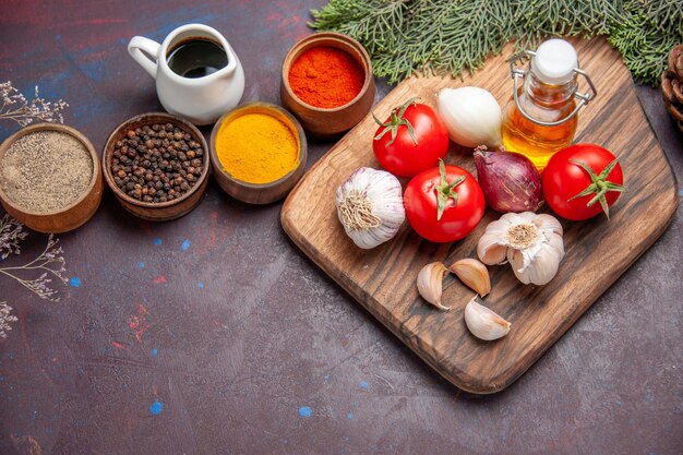 Top view of different seasonings with fresh vegetables on black