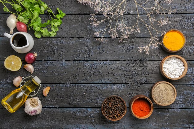 Top view different seasonings with greens on dark desk