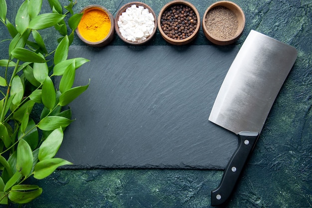 Free photo top view different seasonings with knife on dark blue background photo food spice salt pepper