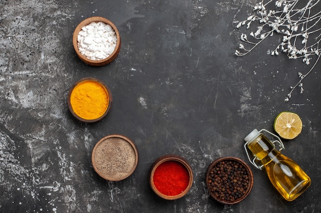 Top view different seasonings with oil on dark table spice color pepper