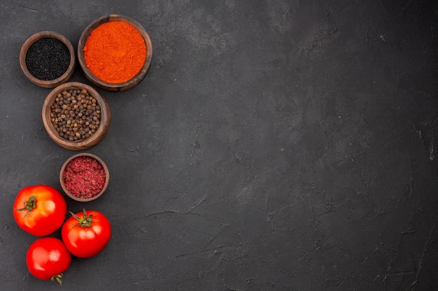 Top view different seasonings with tomatoes on grey background spicy pepper color fresh