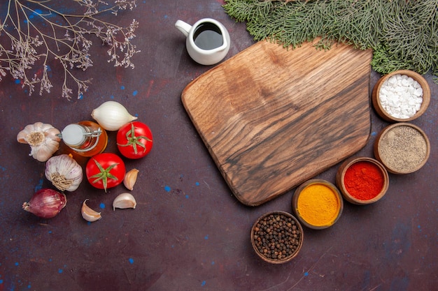 Top view of different seasonings with vegetables on black