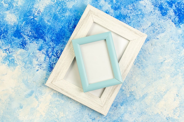 Top view different sizes blank picture frames on blue white grunge copy place