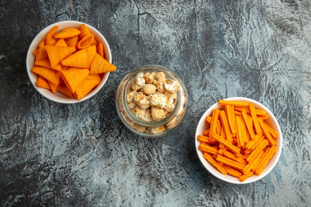 Top view different snacks popcorn rusks and cips on a dark surface