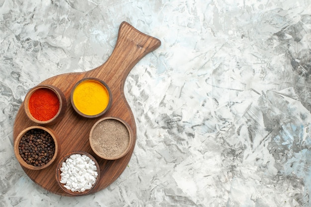 Free photo top view of different spices on cutting board on white background