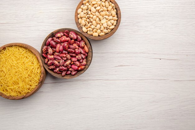 Top view different stuffs in small wooden bowls thin pasta tubes beans on wooden table