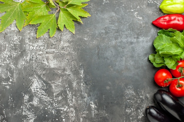 Top view different vegetables tomatoes peppers aubergines on grey background