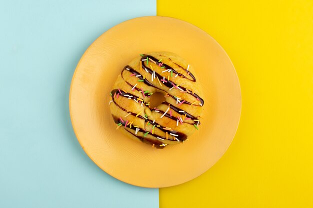 top view donuts inside orange plate on the blue yellow desk