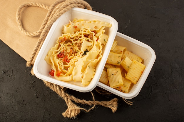 A top view dough meal with dried green herbs inside white bowl and package on dark