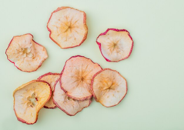 Top view of dried apple slices on light blue background