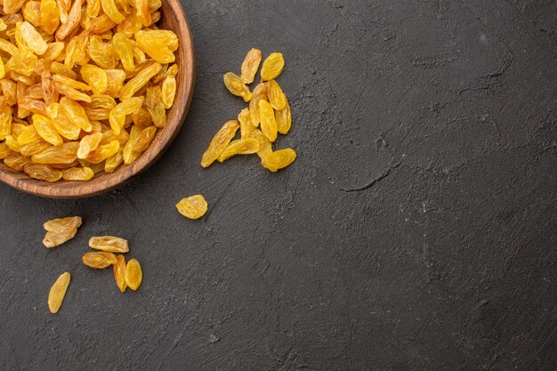 Top view of dried grape raisins inside plate on a grey surface